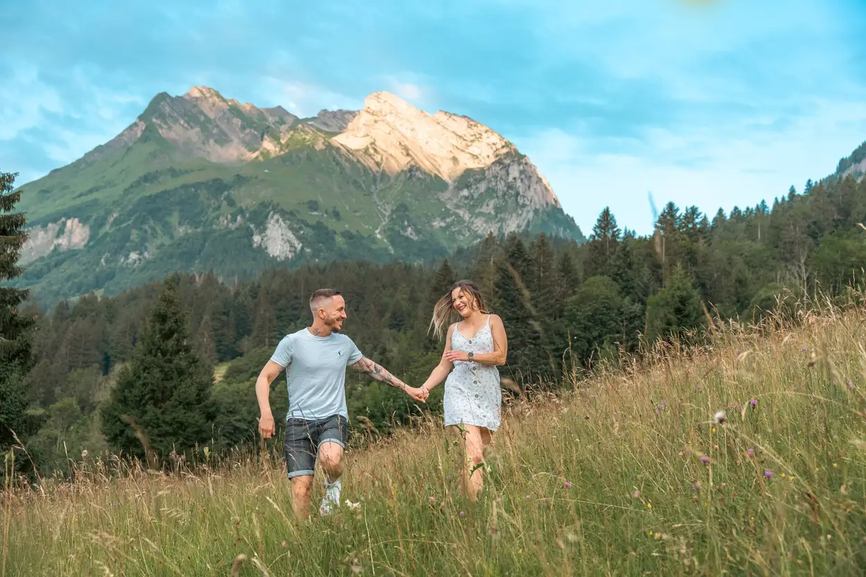 Verlobtes Paar rennt durchs Feld mit Bergpanorama – Verlobungsshooting Toggenburg